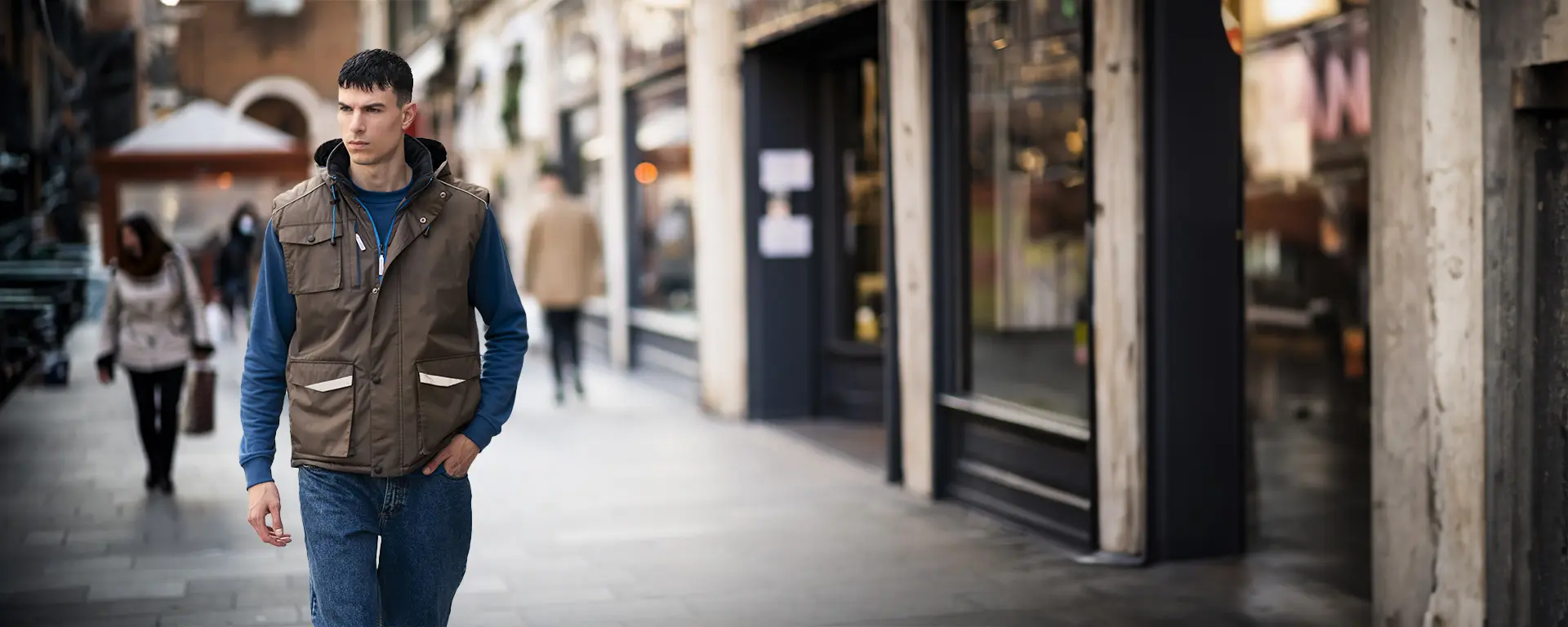 Un uomo in gilet cammina per la strada indossando abbigliamento sottozero da lavoro.